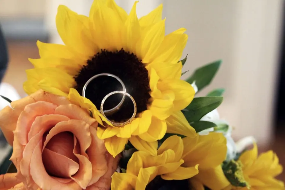 Alianzas de boda apoyadas en un girasol y una rosa