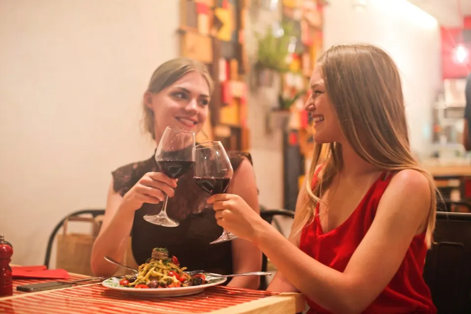 Dos amigas brindando con vino tinto en un aniversario en un restaurante de Ronda