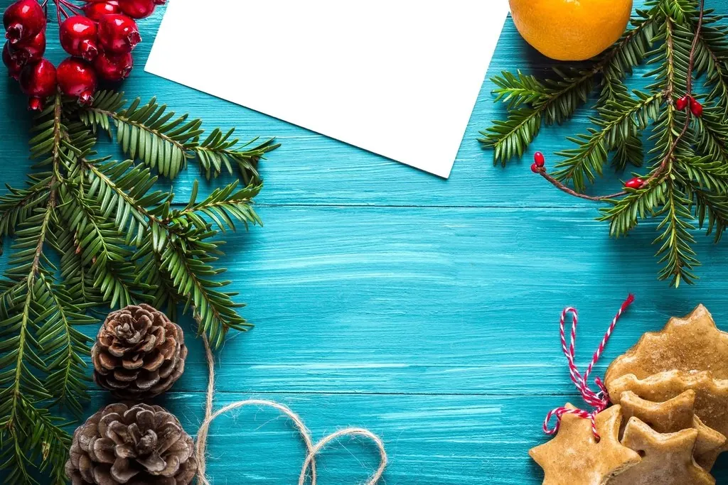 Ramas de abeto, piñas y galletas navideñas sobre fondo turquesa