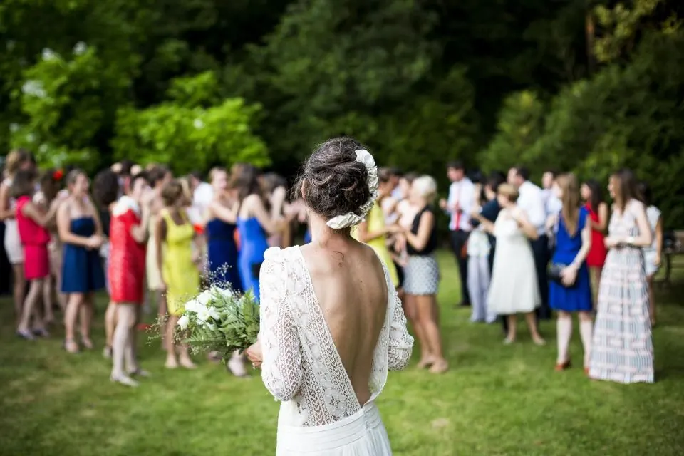 Novia con ramo de espaldas ante los invitados en un jardín de boda en Málaga