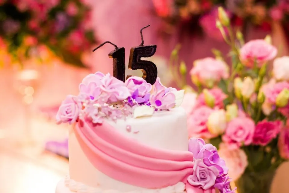 Tarta rosa con flores y vela de quince años en una fiesta de cumpleaños en Ronda